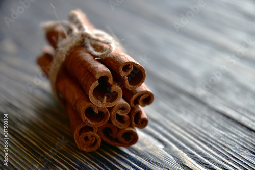 Cinnamon sticks on a dark wooden surface bound with rope. Close-up. Side view. Natural light.