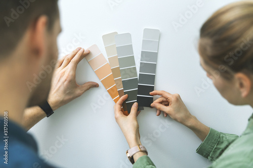 Fototapeta Naklejka Na Ścianę i Meble -  young couple choosing paint color from samples for new home interior design