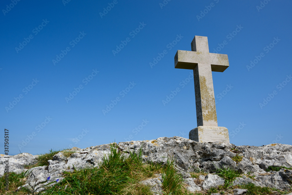 Christian cross on rock over blue sky as copy-space