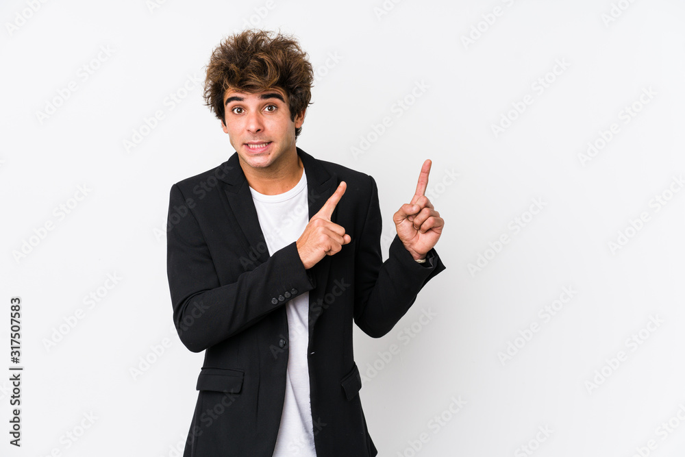 Young caucasian business man against a white background isolated shocked pointing with index fingers to a copy space. Young caucasian business man against a white background isolated shocked pointing with index fingers to a copy space.