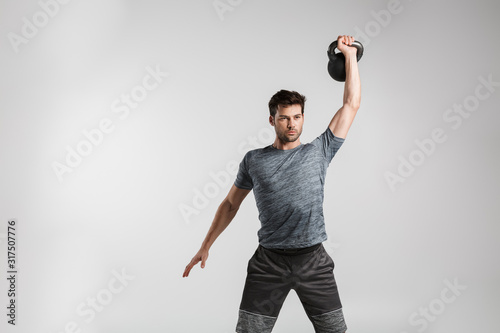 Image of young strong man doing exercise with weight while working out photo