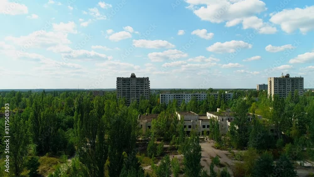 Aerial view of abandoned buildings and streets overgrown with trees in city Pripyat near Chernobyl nuclear power plant. Exclusion Zone. Camera approaching. Sign of USSR on the roof. 4K drone footage. Aerial view of abandoned buildings and streets overgrown with trees in city Pripyat near Chernobyl nuclear power plant. Exclusion Zone. Camera approaching. Sign of USSR on the roof. 4K drone footage.