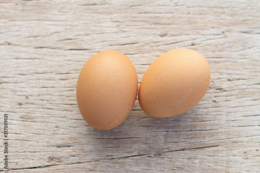 Two brown raw chickens eggs on a wooden background table. Two brown raw chickens eggs on a wooden background table.