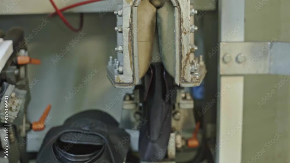 Shoe factory worker puts backside of a shoe to an industrial press machine to gie it a proper form. 