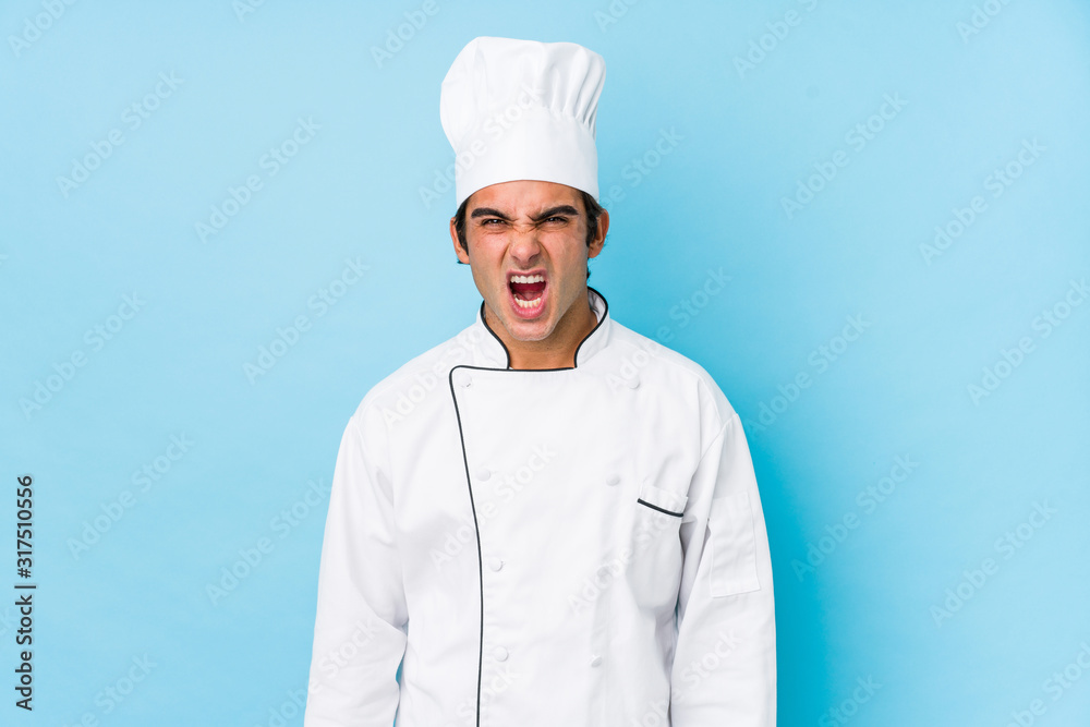 Young cook man isolated screaming very angry and aggressive. Young cook man isolated screaming very angry and aggressive.