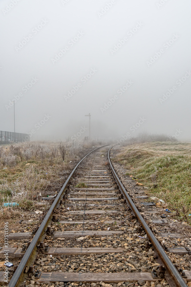 Railway in the fog. Train tracks disappear into strange glowing fog