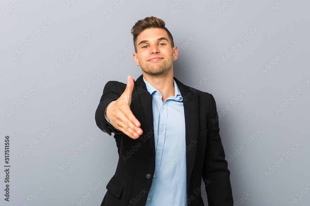 Young handsome caucasian man stretching hand at camera in greeting gesture. Young handsome caucasian man stretching hand at camera in greeting gesture.