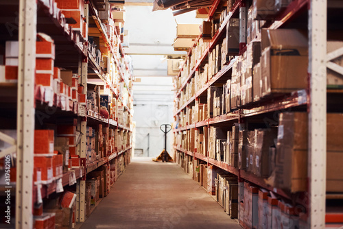 Storage room with pallet truck and many of objects at daytime