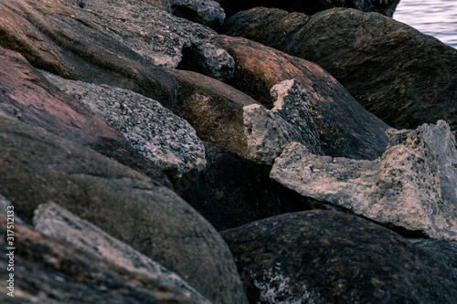 Piles of boulders spread all over the coast; Macro texture of granite and sand