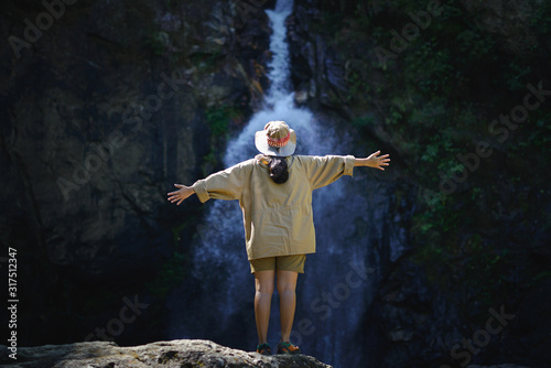 Young woman standing in front of waterfall