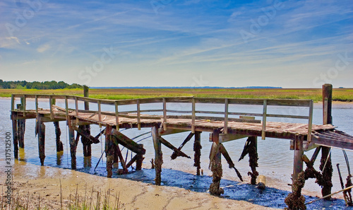 An old pier falling apart on the edge of the marsh and the mud