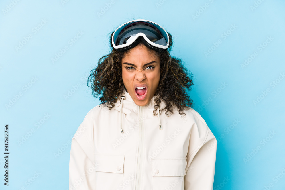 Young african american skier woman isolated screaming very angry and aggressive. Young african american skier woman isolated screaming very angry and aggressive.