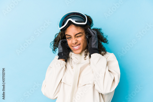 Young african american skier woman isolated covering ears with hands.