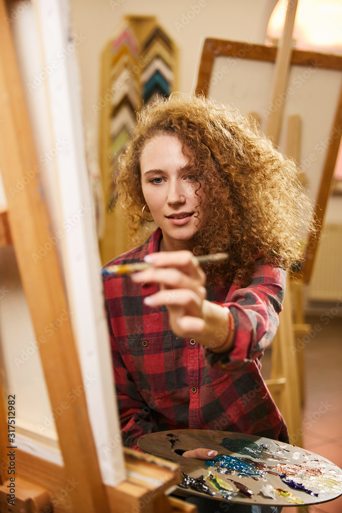 Pretty redhead curly artist with smile draws a painting Pretty redhead curly artist with smile draws a painting