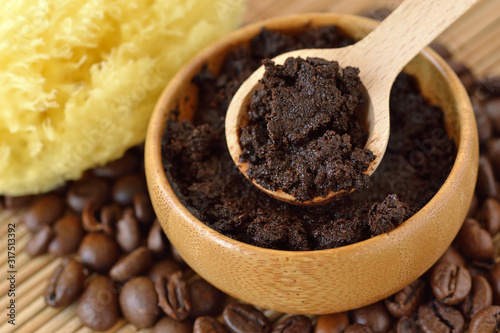 Homemade coffee scrub face mask in wooden bowl with spoon on coffee beans photo