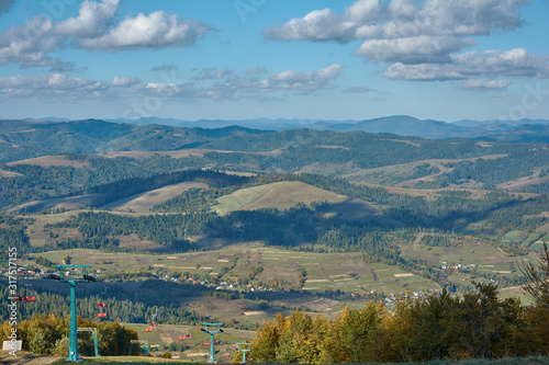 Mountain landscape in Carpathian Mountains, Pylypets, Ukraine. View of the valley and village of Pylypets from Gymba Mountain. Pylons of mountain chairlift on Mount Hymba.