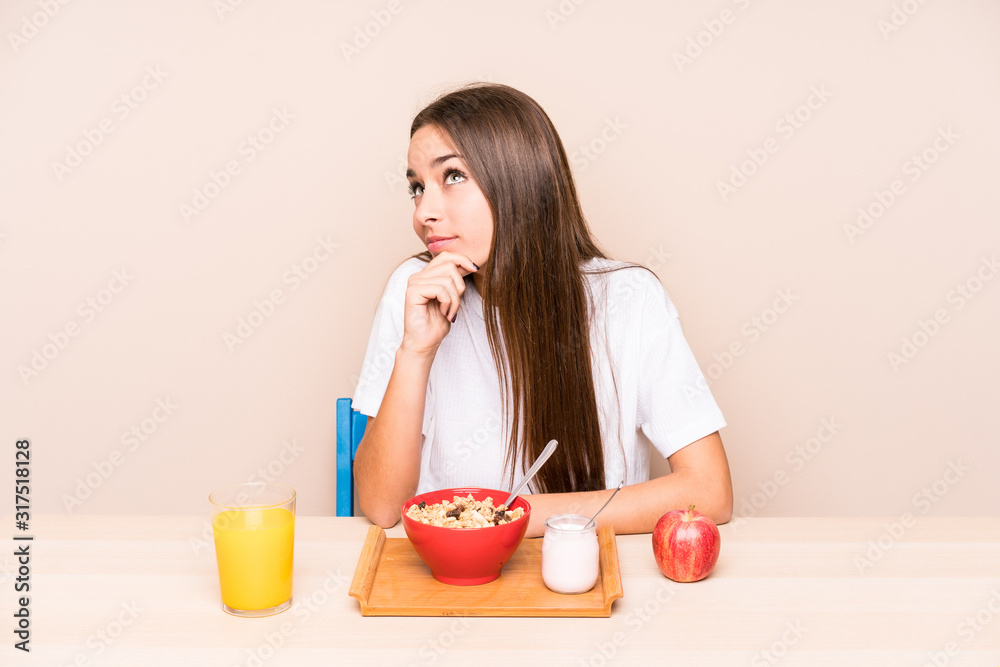 Young caucasian woman having a breakfast isolated looking sideways with doubtful and skeptical expression. Young caucasian woman having a breakfast isolated looking sideways with doubtful and skeptical expression.