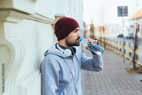 Stampa su tela handsome young man jogging outdoors. drinking water