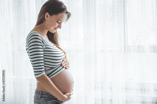 Happy pregnant woman with big belly by the window. Concepts of pregnancy and family Free Download Happy pregnant woman with big belly by the window. Concepts of pregnancy and family - GFXLoad