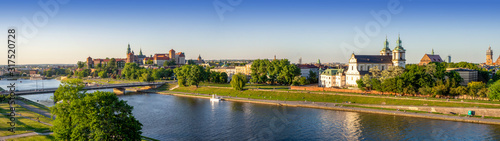 Krakow, Poland. Wide aerial panorama with Vistula river, Wawel cathedral and castle, Skalka church and Paulinite monastery, bridge, parks and promenades along the riverside. Summer, sunset light