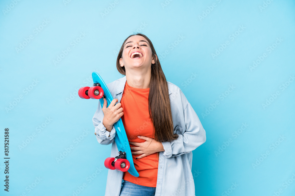 Young caucasian skater woman isolated on blue background Young caucasian skater woman isolated on blue background