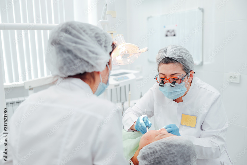 female dentist checks teeth in dental office with assistant female dentist checks teeth in dental office with assistant