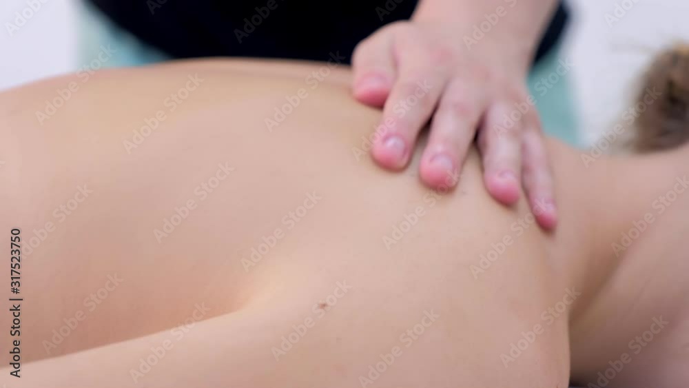 Doctor woman making healing body neck spine massage to patient girl in clinic, side view. Medical therapeutic massage. Massagist, therapist treats patient lying in couch. Treatment, cure, procedure. Doctor woman making healing body neck spine massage to patient girl in clinic, side view. Medical therapeutic massage. Massagist, therapist treats patient lying in couch. Treatment, cure, procedure.