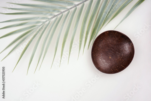 Palm leaf decoration, empty coconut shell bowl on white background. Tropical frame, natural product, ingredient concept. Top view, flay lay, copy space