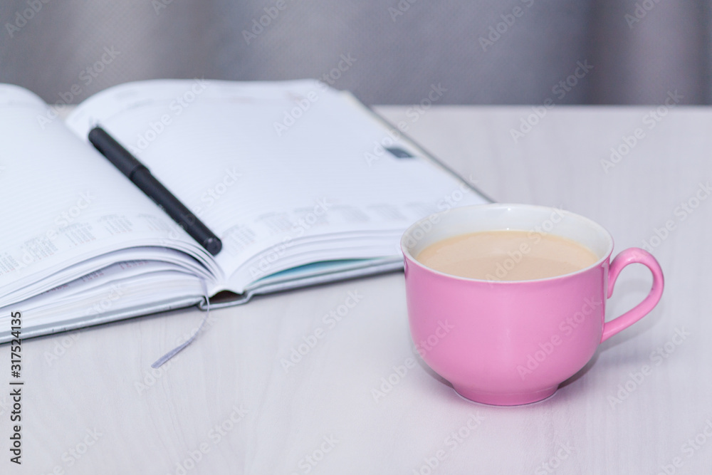 Pink cup of coffee, open notebook on wooden desk table. Freelancer or bloger, copywriter concept.