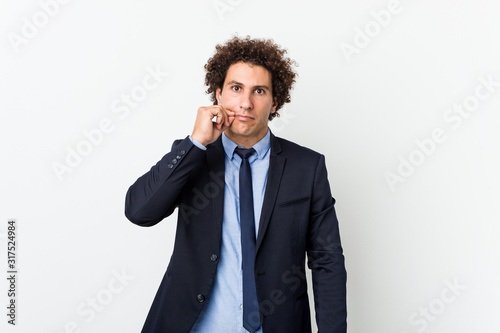Young business curly man against white background with fingers on lips keeping a secret.