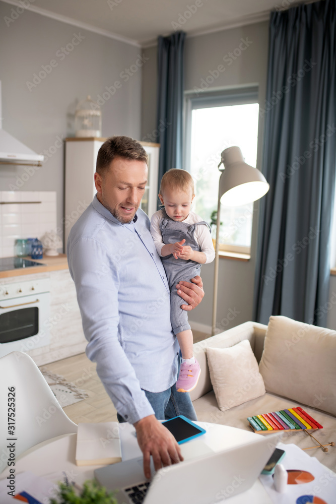 Man in a blue shirt standing and holding his baby girl