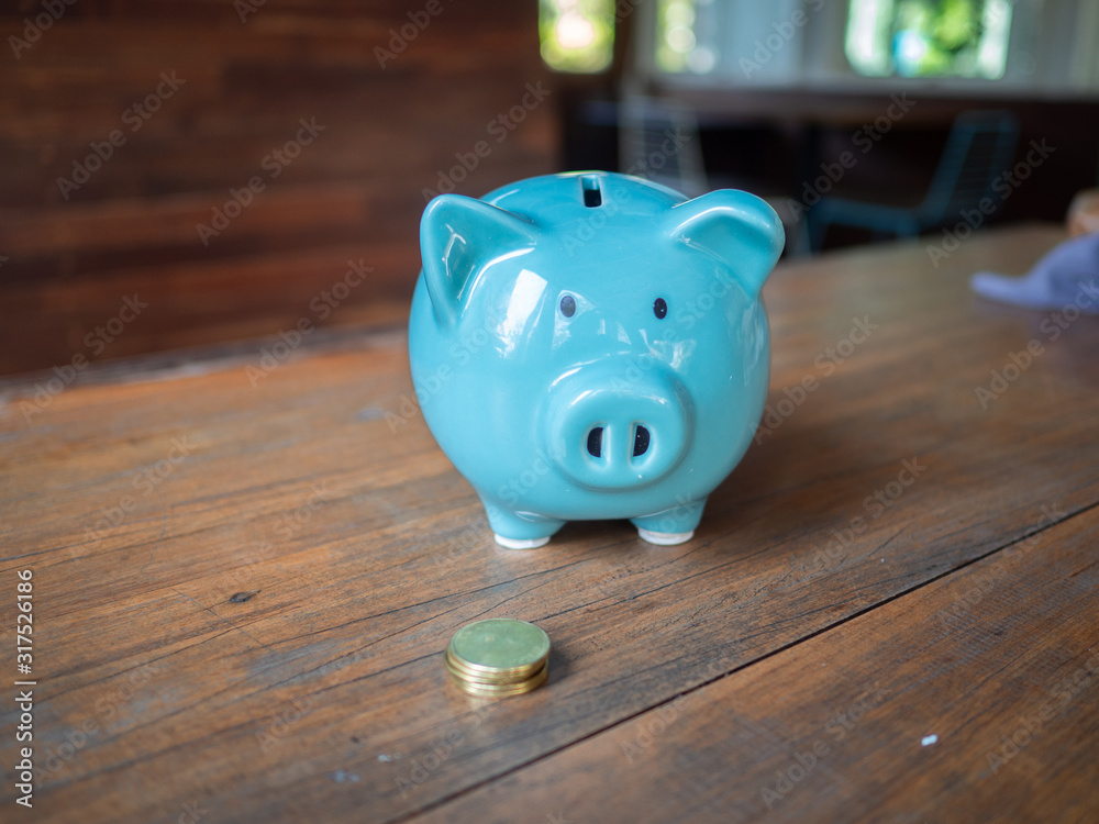 Fototapeta premium Blue piggy bank with coins. The idea of saving money for life