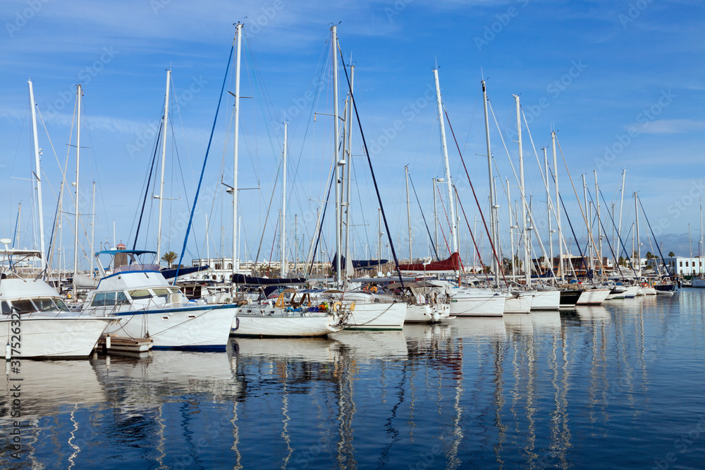 Sailing, fishing boats, yachts anchored in a small sea port, on a summer day .