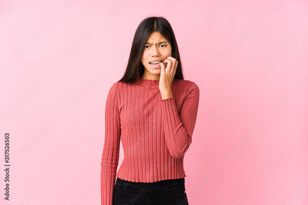 Young chinese woman posing isolated biting fingernails, nervous and very anxious.