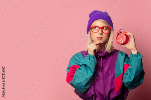 Beautiful blonde woman in 90s clothes with alarm clock