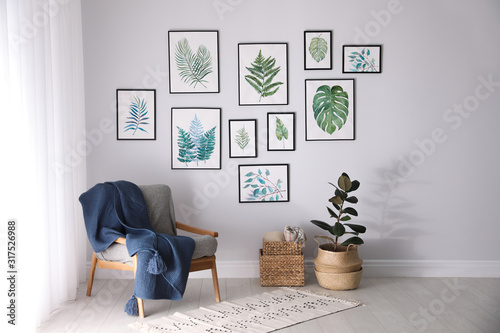 Fototapeta Naklejka Na Ścianę i Meble -  Beautiful paintings of tropical leaves on white wall in living room interior