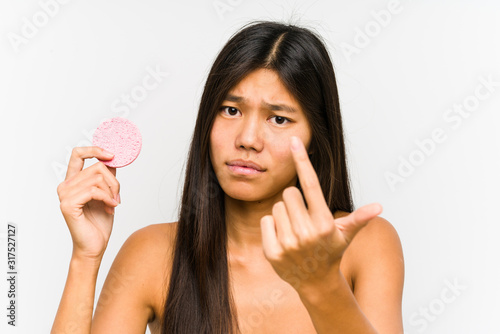 Young chinese woman holding a facial disk isolated pointing with finger at you as if inviting come closer.