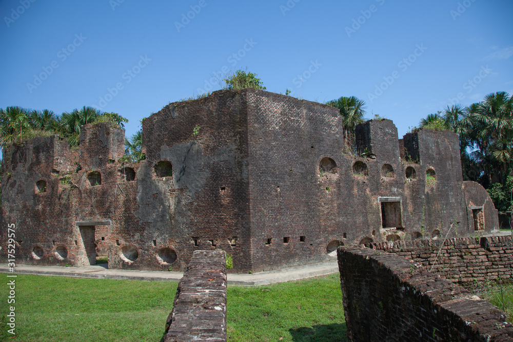 Old brick fortress walls of Fort Zeelandia in the subtropics against a background of green trees and palm trees, Guyana. Medieval architecture, world tourism.