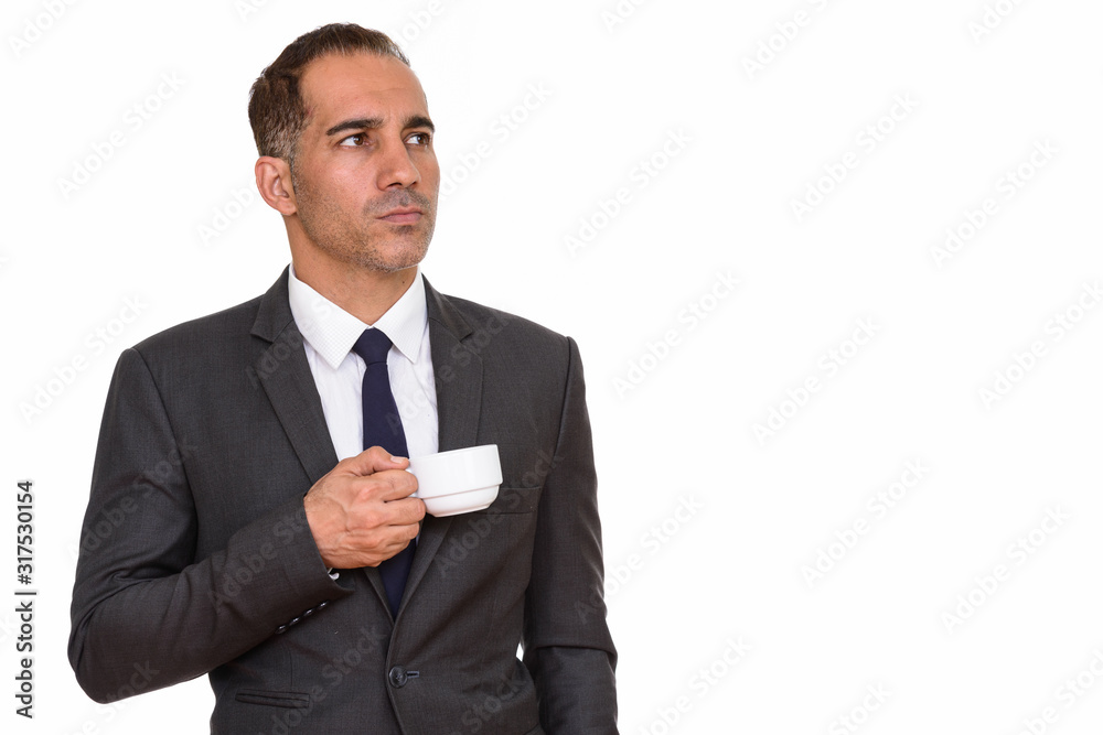 Mature handsome Persian businessman holding coffee cup while thinking Mature handsome Persian businessman holding coffee cup while thinking