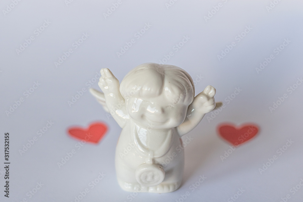 Ceramic figurine on a blue background and red hearts in blur . Valentine's Day. Selective focus. Ceramic figurine on a blue background and red hearts in blur . Valentine's Day. Selective focus.