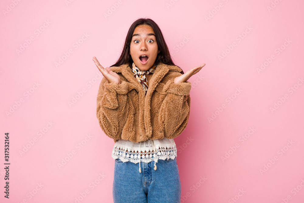 Young mixed race indian woman wearing a short sheepskin coatsurprised and shocked. Young mixed race indian woman wearing a short sheepskin coatsurprised and shocked.