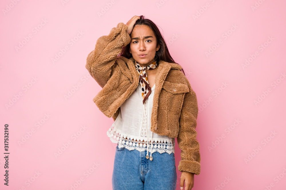Young mixed race indian woman wearing a short sheepskin coattired and very sleepy keeping hand on head.