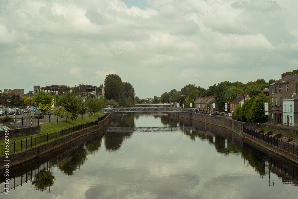 View of part of the city of Kilkenny in Ireland, crossed by the River Nore. Reflections on the water. Cloudy day.