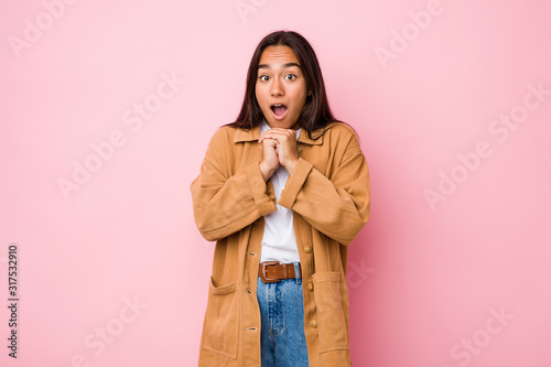 Young mixed race indian woman isolated praying for luck, amazed and opening mouth looking to front.
