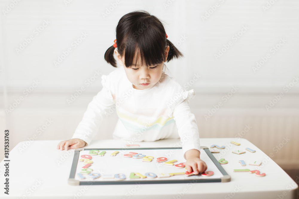 toddler girl learning math on white board against white background toddler girl learning math on white board against white background