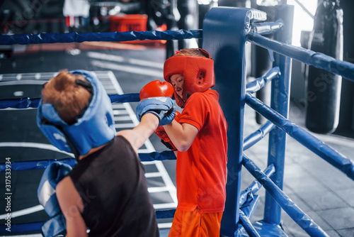 Two boys in protective equipment have sparring and fighting on the boxing ring