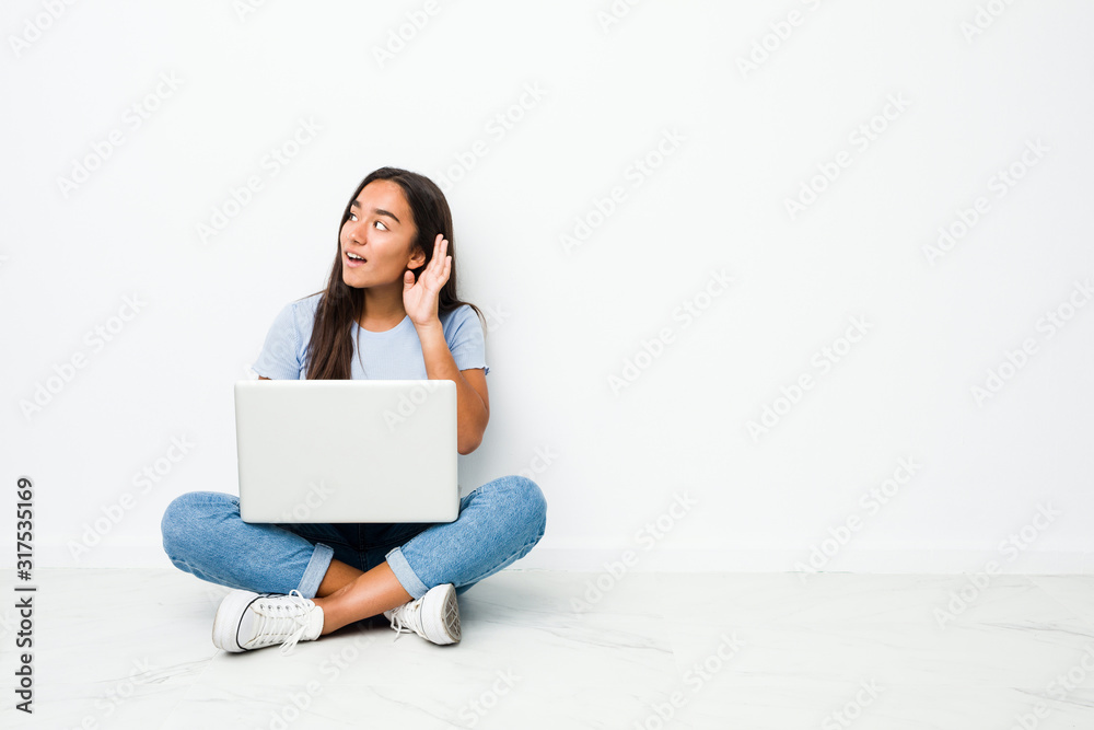 Young mixed race indian woman sitting working on laptop trying to listening a gossip. Young mixed race indian woman sitting working on laptop trying to listening a gossip.