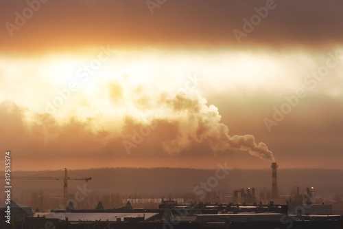 Industrial dull gray look with low cloudiness and smoky smog in the city, sunlight shines through the clouds.