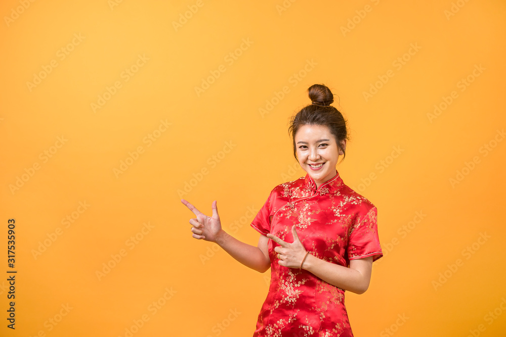 Asian woman smile in Chinese dress presenting free space yellow background. Chinese new year festival. Asian woman smile in Chinese dress presenting free space yellow background. Chinese new year festival.