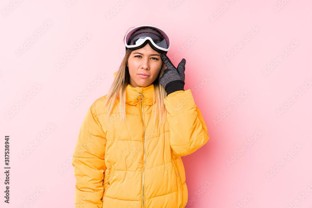 Young caucasian woman wearing a ski clothes in a pink background showing a disappointment gesture with forefinger. Young caucasian woman wearing a ski clothes in a pink background showing a disappointment gesture with forefinger.